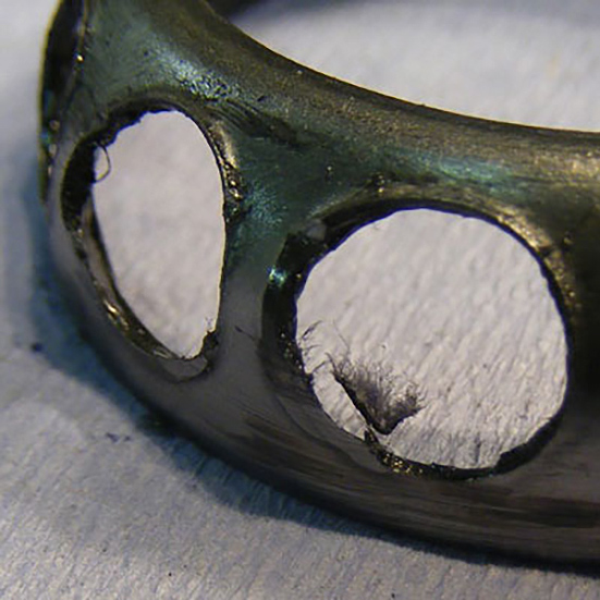 An angular contact bearing cage deformed due to rubbing contact with other assembly parts